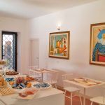 Geräumiger und gut beleuchteter Innenraum eines Gemeinschaftsbereichs mit einfachen Möbeln und einem Buffet.