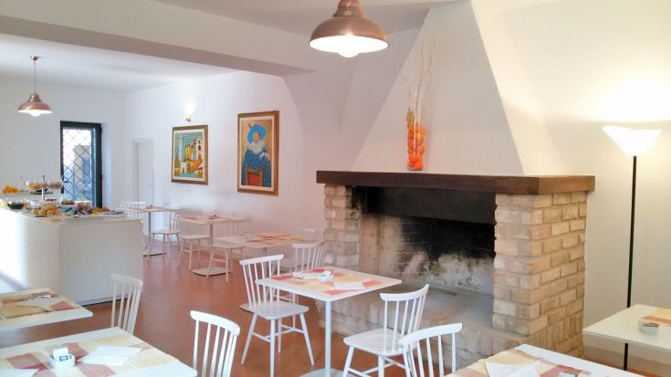 Gemütliches Esszimmerinnere mit einfachen Tischen und Wanddekorationen.