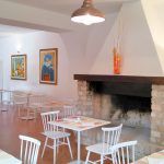 Gemütliches Restaurantinterieur mit weißen Tischen und Wanddekorationen.