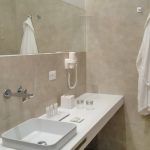 Innenansicht eines modernen Badezimmers mit gut platziertem Waschbecken und Spiegel, einfach eingerichtet.