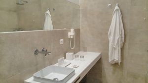 Ein modernes Badezimmer mit einem eleganten Waschbecken, hängenden Handtüchern und schlichter Einrichtung.