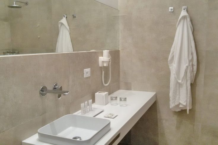 Ein modernes Badezimmer mit schlichter Gestaltung, ausgestattet mit einem Waschbecken und einem praktisch aufgehängten Bademantel.