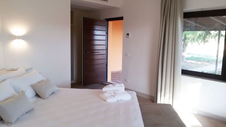 Ein schlichtes Schlafzimmer mit einem Doppelbett und Blick auf einen schönen Garten.