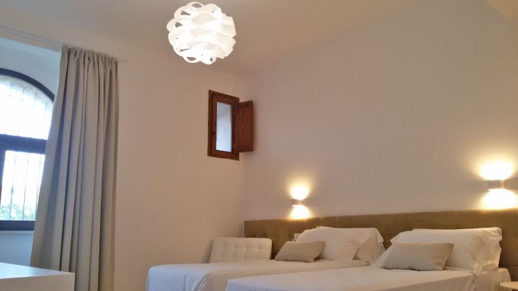 Geräumiges und gut beleuchtetes Zimmer mit Einzelbetten und schlichten, aber eleganten Möbeln.