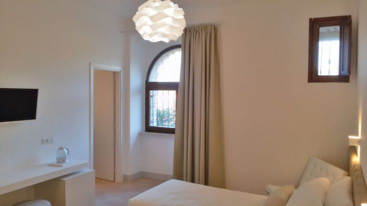 Helles Zimmerinterieur mit einfachen Möbeln und einem großen Fenster.