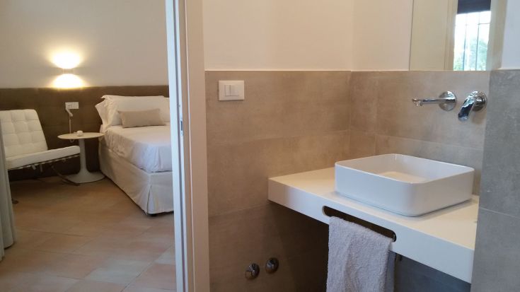 Ein minimalistisches Schlafzimmer neben einem hellen und funktionalen Badezimmer.