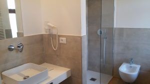 Ein modernes Bad mit Dusche, einfachem Waschbecken und minimalistischer Einrichtung.