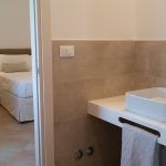 Ein einfaches Badezimmer mit einem weißen Waschbecken und einer Tür, die zu einem Schlafzimmer führt.