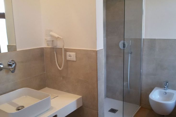 Zeitgemäßes Badezimmer mit Dusche, Waschbecken und Bidet, eingerichtet mit hellen Wänden und einfachen Details.