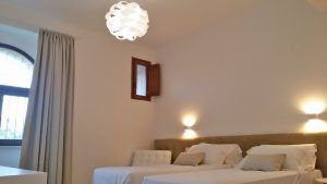 Einfaches Zimmer mit Einzelbetten, sanfter Beleuchtung und dezentem Dekor.