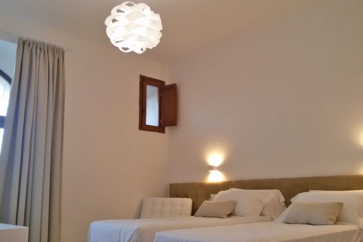 Einfaches Zimmer mit Einzelbetten, sanfter Beleuchtung und praktischer Einrichtung.