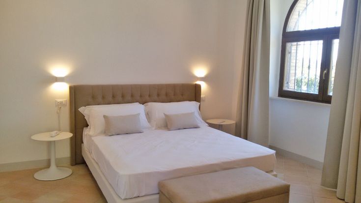 Ein einfaches und gut beleuchtetes Schlafzimmer mit einem Doppelbett und modernen Dekorationen.