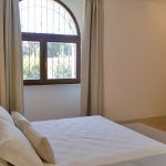 Ein gut beleuchtetes Doppelzimmer mit Blick auf einen gepflegten Garten.