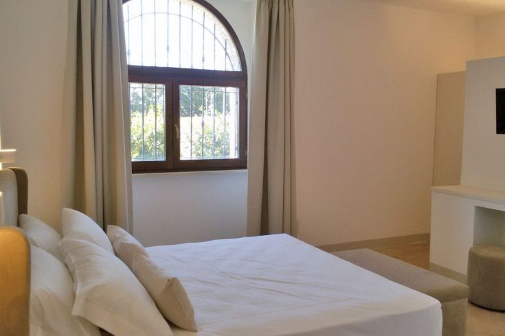 Helle und einfache Zimmer mit einem Fenster, das auf eine grüne Fläche blickt.