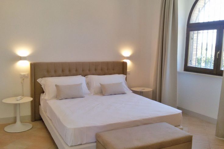 Einfaches und helles Zimmer mit einem Doppelbett und grundlegenden Möbeln.