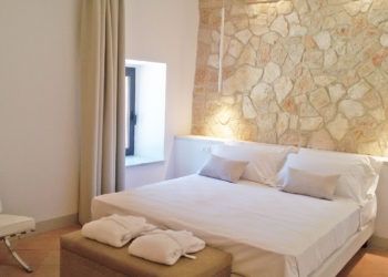 Moderne Doppelzimmer mit Steinwänden und komfortablen Betten.