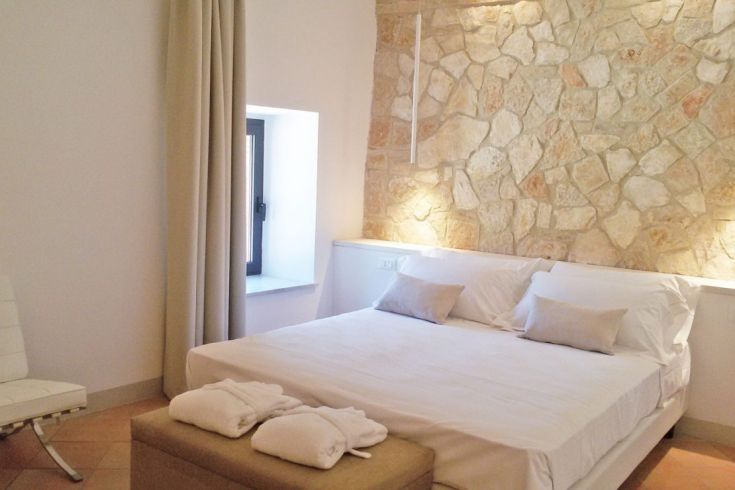 Moderne, gut beleuchtetes Schlafzimmer mit einer Steinwand und ordentlich angeordneten Betten.