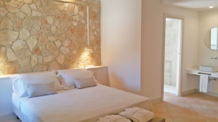 Eine einfache Wohnung mit Steinmauern, ausgestattet mit einem Doppelbett und einem funktionalen Badezimmer.