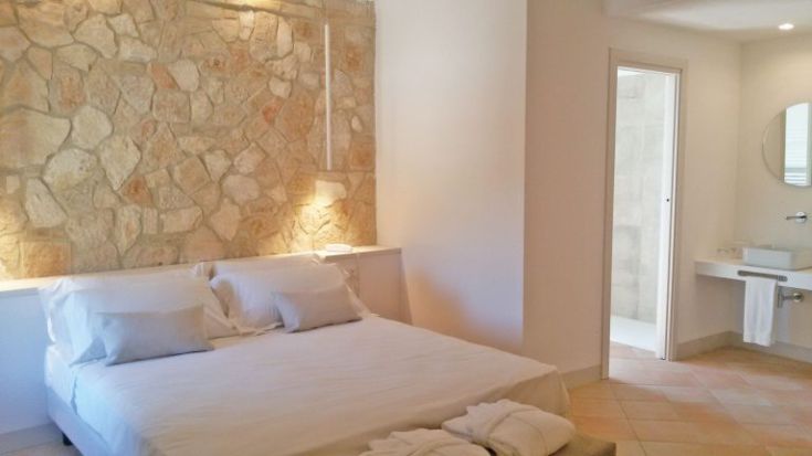 Einfaches Zimmer mit Steindetails, weißen Betten und eigenem Bad.