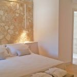 Helle Zimmer mit Steinwand und eleganten Betten, gemütliche Atmosphäre.