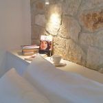 Eine gemütliche Leseecke mit Büchern und einer Tasse auf einem Tisch neben einer Steinmauer.