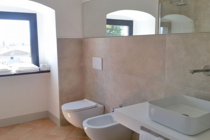 Modernes und schlichtes Badezimmer mit modernen Sanitäranlagen und großen Fenstern, die natürliches Licht bieten.