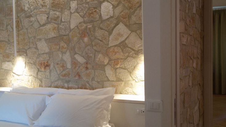 Eine einfache Ecke eines Schlafzimmers mit Steinwänden und weißen Betten.