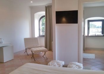 Innenansicht eines modernen, schlichten Schlafzimmers mit Blick auf eine ruhige Naturlandschaft.