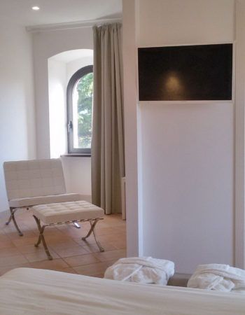Ein raffiniertes Schlafzimmerinterieur mit wandmontiertem Fernseher und panoramischer Aussicht durch das Fenster.
