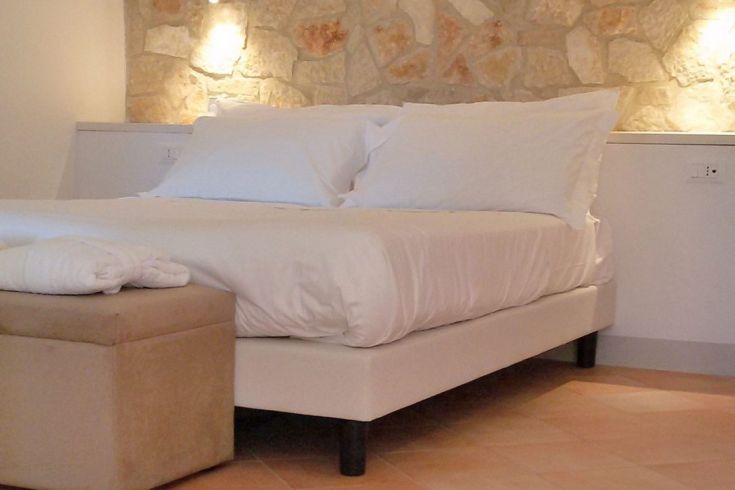 Gemütliches Zimmer mit Steinwand und einem bequemen Bett.