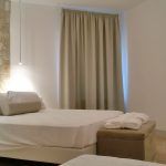 Moderne Zimmer mit Einzelbetten und hellen Vorhängen, einfache und gemütliche Atmosphäre.