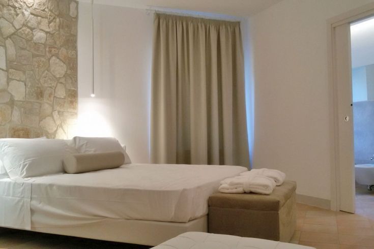 Ein helles Zimmer mit einem großen Bett und schlichten Dekorationen.