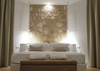 Geräumiges Schlafzimmer mit einer Steinwand und sanfter Beleuchtung, einfache und funktionale Einrichtung.