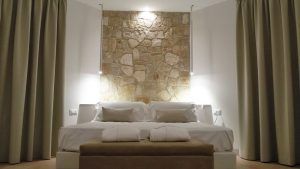 Gemütliches Zimmer mit bequemen Betten und sichtbaren Steinmauern, einfach eingerichtet.