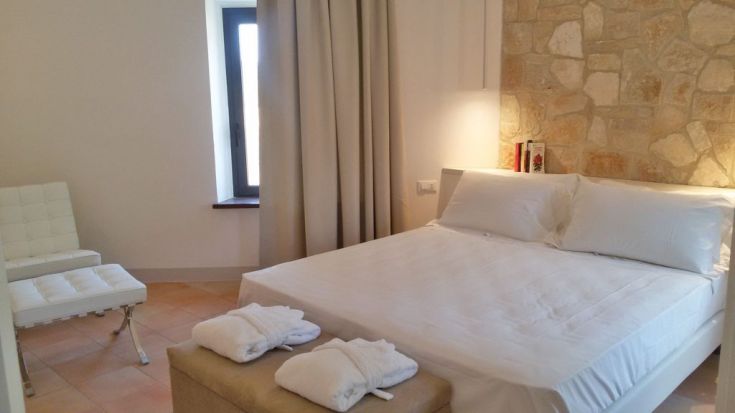 Schlafzimmer mit weißen Betten und Steindetails. Einfache und komfortable Einrichtung.