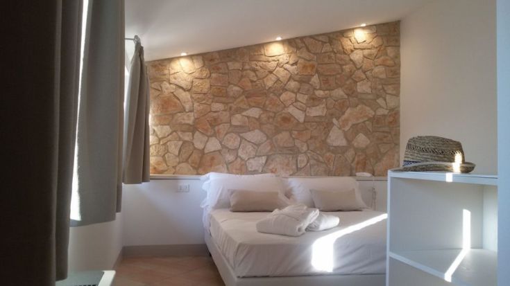 Ein gemütliches Zimmer mit einer Steinwand und sanfter Beleuchtung, ausgestattet mit einfacher und funktionaler Einrichtung.