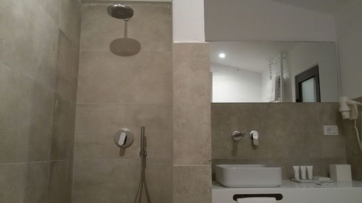 Innenansicht eines modernen Badezimmers mit Dusche und Waschbecken im schlichten Design.