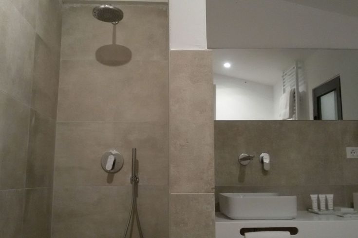 Ein modernes Badezimmer mit Dusche und Waschbecken, eingerichtet in hellen Farben und einfachen Oberflächen.