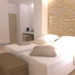 Schlichte Zimmer mit Doppelbett und Steinwand, beleuchtet von natürlichem Licht.