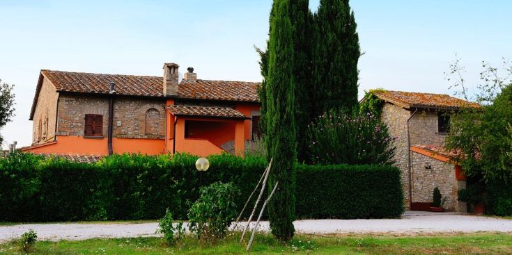 Ein malerisches Landhaus umgeben von einem Garten mit Bäumen.