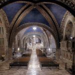 Das Innere einer Kirche mit gotischen Bögen und einer blauen Decke, die mit Sternen verziert ist.