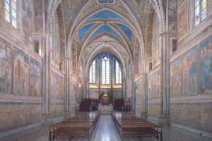 Innenszene einer Kirche mit dekorativen Fresken an den Wänden und gotischen Architekturdetails.