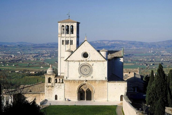Szene der Basilika San Francesco, umgeben von Bäumen und grünen Wiesen.
