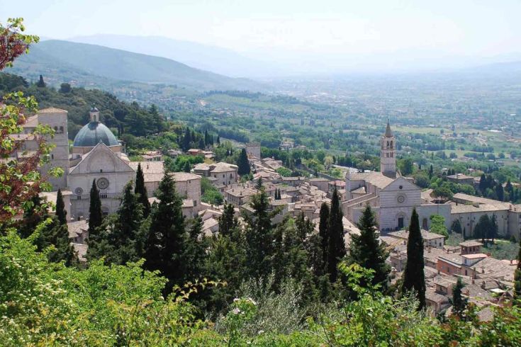 Szene eines alten Dorfes mit Bäumen und Bergen im Hintergrund.