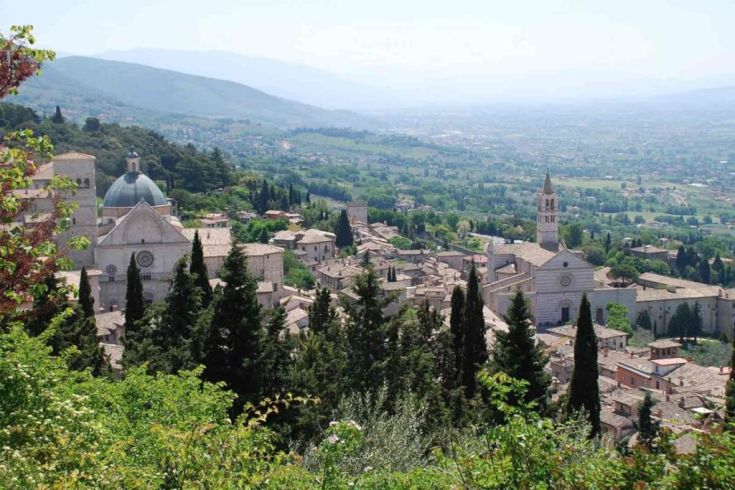 Ein Panoramablick auf eine typische umbrische Hügellandschaft mit historischen Gebäuden und Bäumen.