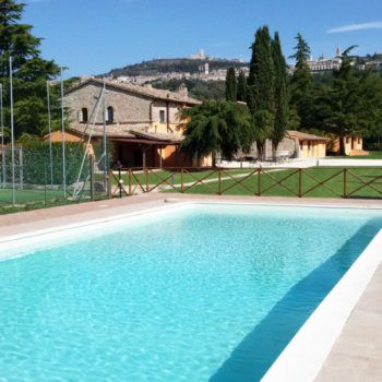 Szene eines klaren Pools, umgeben von üppiger grüner Natur, mit einem rustikalen Haus in der Nähe.