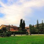 Ein Palast umgeben von Grün, mit Bäumen und einem klaren Himmel darüber.