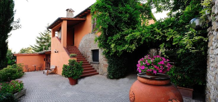 Szene einer Villa, umgeben von einem Garten mit Blumen und einfachen architektonischen Elementen.