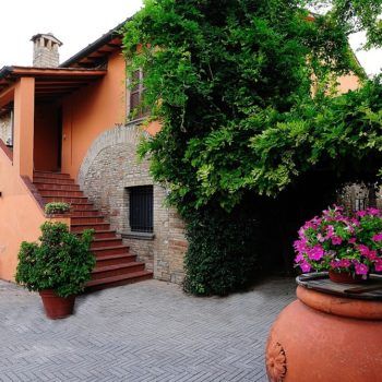 Eine rustikale Villa, umgeben von Grün, mit einer Steintreppe und blühenden Blumenbeeten. Ein idealer Ort für einen ruhigen Aufenthalt.