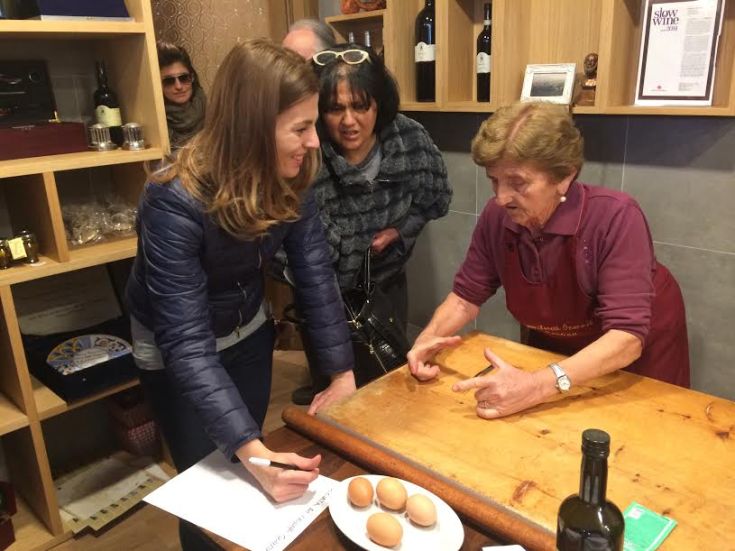 Eine Kundin tauscht frische Eier gegen eine Flasche Wein mit einer Verkäuferin.